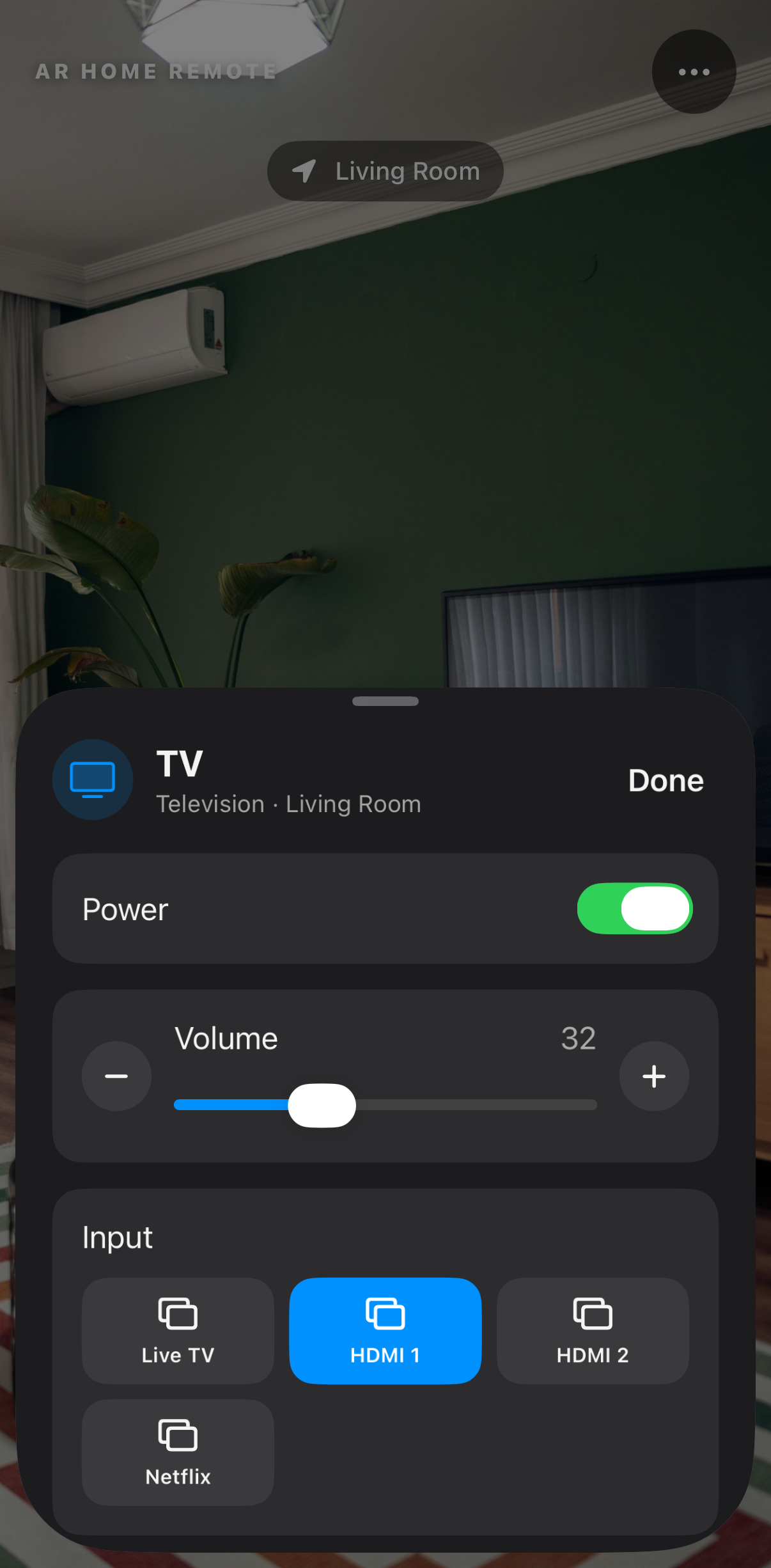 The TV control sheet risen to half height over the same room — power on, volume at 32, the input row — with the camera view still live above it.